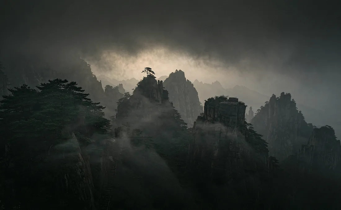 Layered Wudang mountain peaks rising out of dawn mist, with a stone stairway disappearing into the cloud
